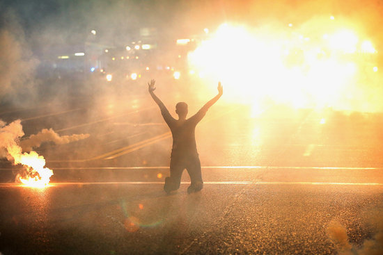 A women knelt in the streets with her hands up as tear gas filled the air. A women knelt in the streets with her hands up as tear gas filled the air.